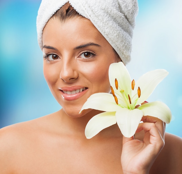 Smiling woman in towel with lily flower