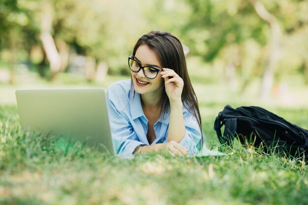 Smiling woman using laptop in citypark at sunny day