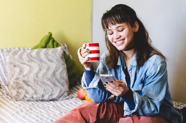 ベッドで電話を使って笑顔の女性