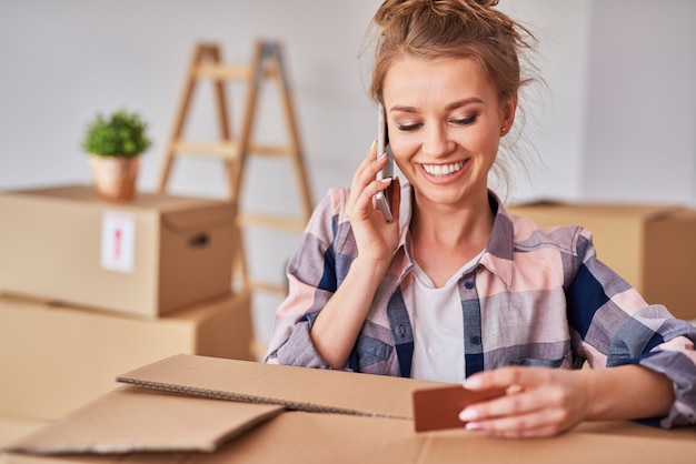 Foto gratuita donna sorridente che usa il telefono mentre cambia casa