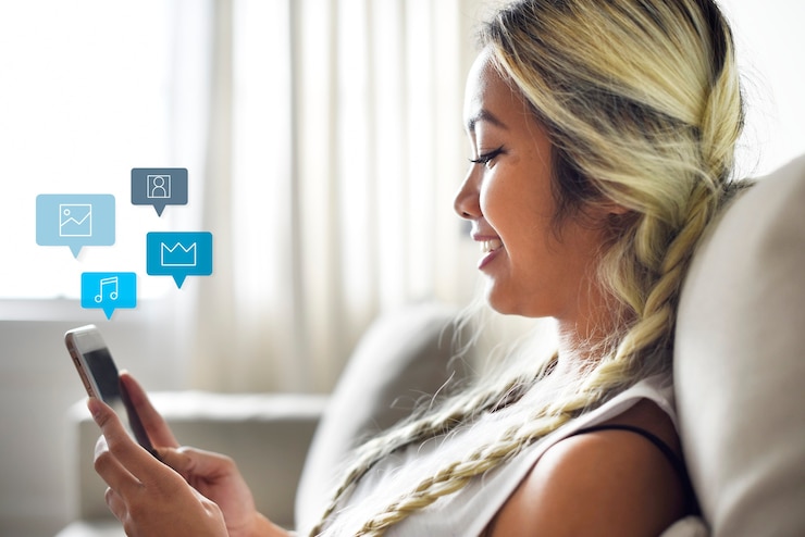 Free Photo smiling woman using a smartphone on a couch