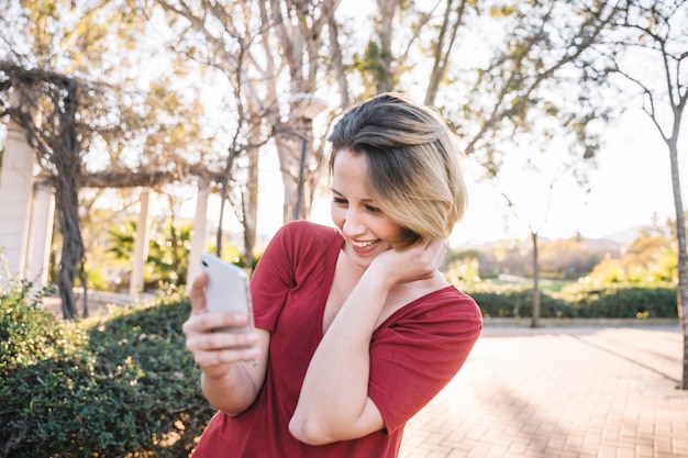 スマートフォン、公園で笑顔の女性