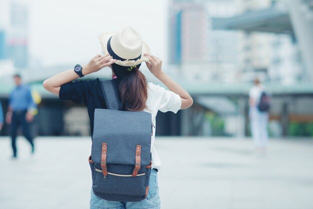 Smiling woman walking outdoors, young lady admiring city sight with walkway and buildings in background.