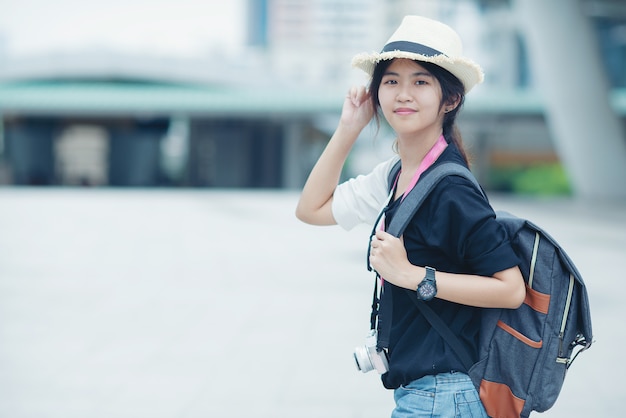 Smiling woman walking outdoors, young lady admiring city sight with walkway and buildings in background. 