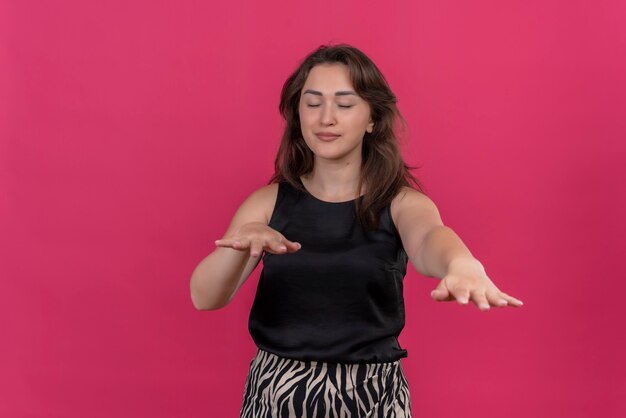 Smiling woman wearing black undershirt looking for on pink wall