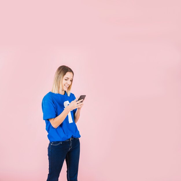 Улыбка женщины носить футболку facebook с помощью мобильного телефона