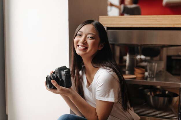 Smiling woman in white t-shirt posing with front in her hands in kitchen