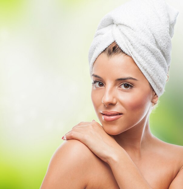 Smiling woman in white towel with hand over shoulder