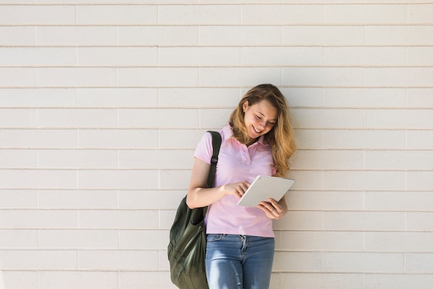 Smiling woman with backpack using tablet on white background