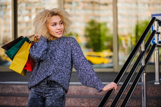 Free photo smiling woman with bags on stairs