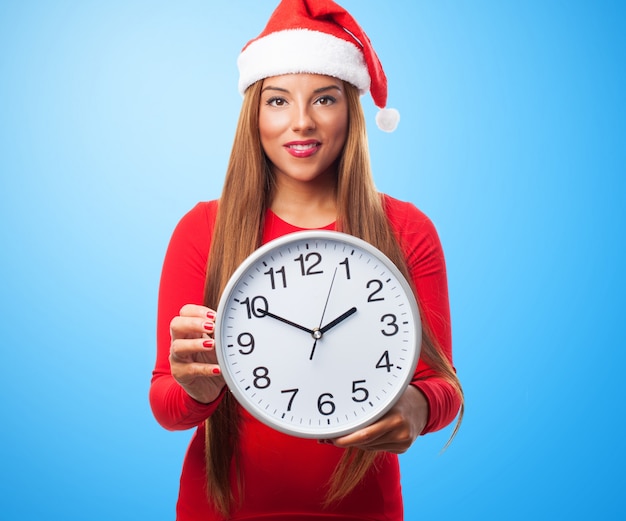 Smiling woman with a big clock and santa's hat