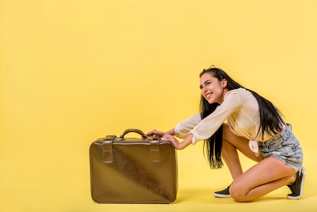 Бесплатное фото Улыбающаяся женщина с большим чемоданом