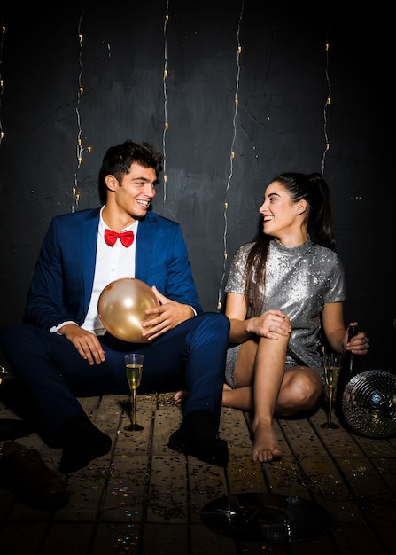 Smiling woman with bottle near happy man with balloon near glasses 