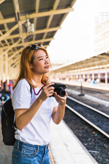 Smiling woman with camera on platform 