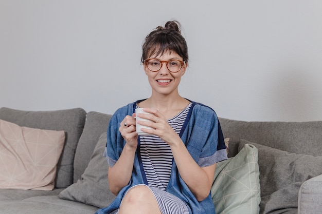 Smiling woman with coffee on couch