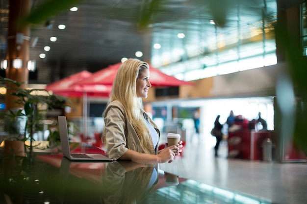 Foto gratuita donna sorridente con caffè in piedi nella zona di attesa