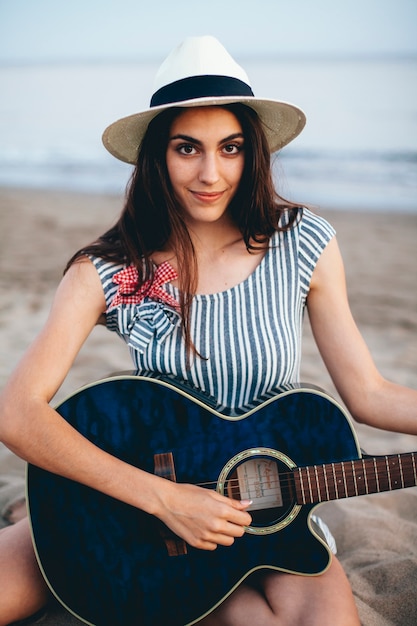 Foto gratuita donna sorridente con la chitarra sul litorale