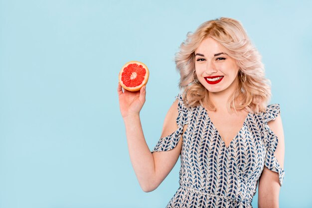 Smiling woman with half of grapefruit