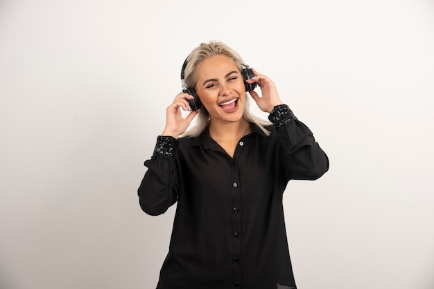 Smiling woman with headphones standing on white background. High quality photo