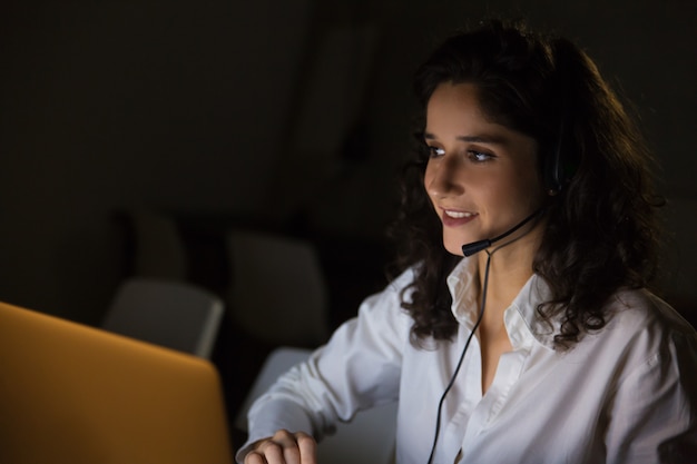 Free photo smiling woman with headset in dark office