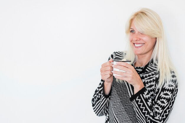 Smiling woman with hot beverage looking away