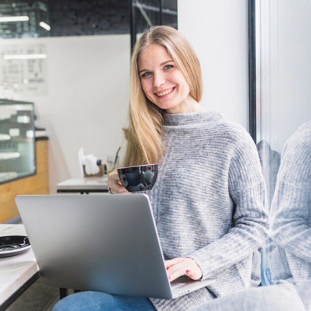 Smiling woman with laptop at cafe