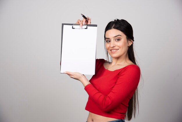 smiling woman with long hair showing a clipboard with pencil.