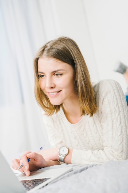 Smiling woman with pen browsing laptop