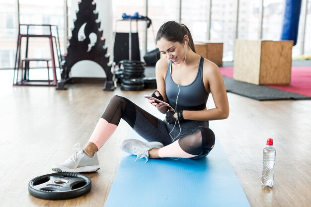 Smiling woman with phone in gym