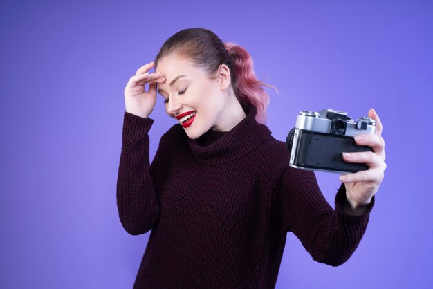 Smiling woman with red lips tries to take selfie with a camera