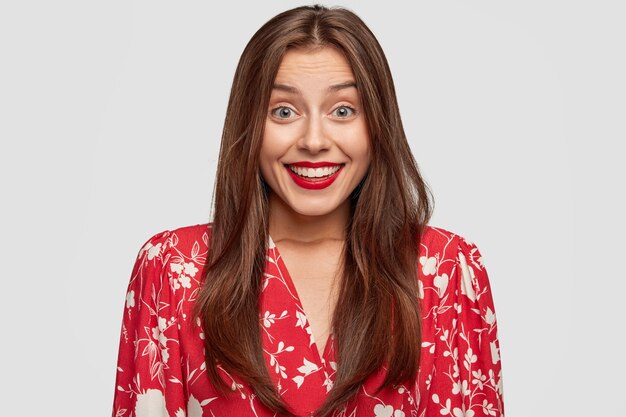 smiling woman with red lipstick posing against the white wall