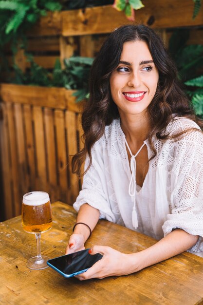 Smiling woman with smartphone and beer