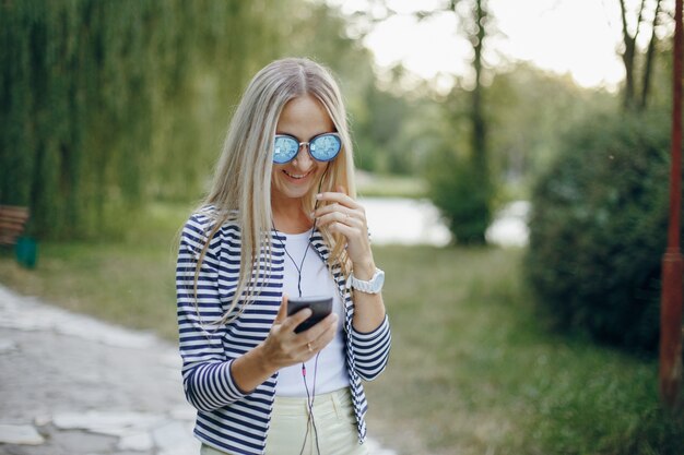 Smiling woman with sunglasses typing on a mobile