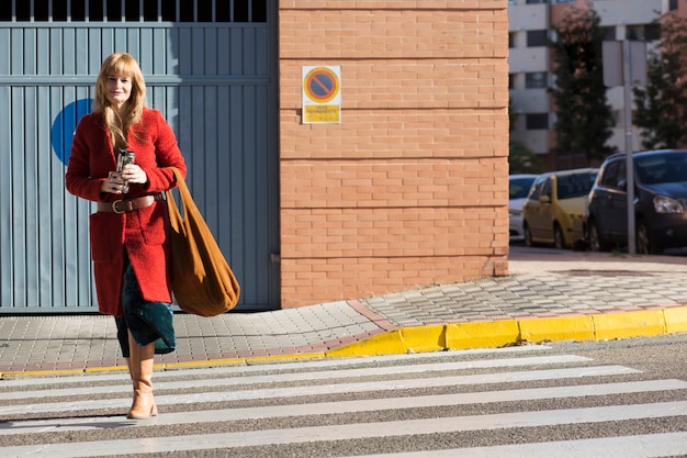 Smiling woman with thermos crossing street