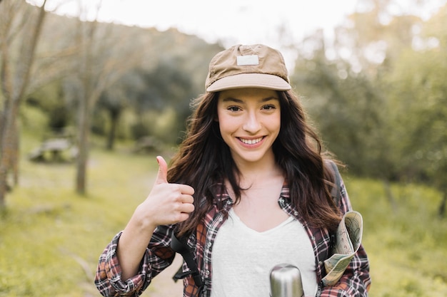 Smiling woman with thermos gesturing thumb-up