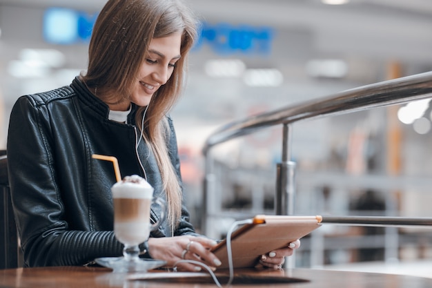 Smiling woman with white headphones and a smoothie on the table