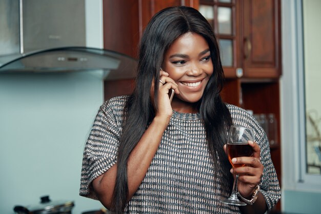 Smiling woman with wineglass speaking on phone