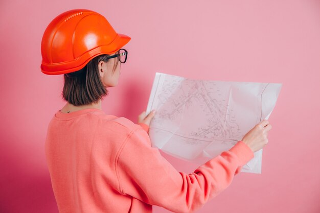 Усмехаясь построитель работника женщины розовом фоне. Строительный шлем.