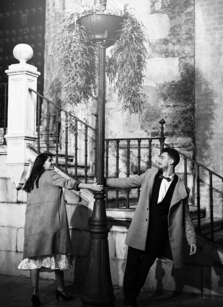 smiling woman and young man whirling around street lamp