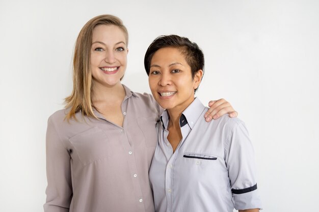 Smiling women embracing and looking at camera