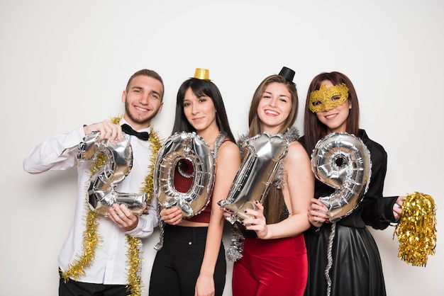 Smiling women and man in evening wear with balloons numbers 