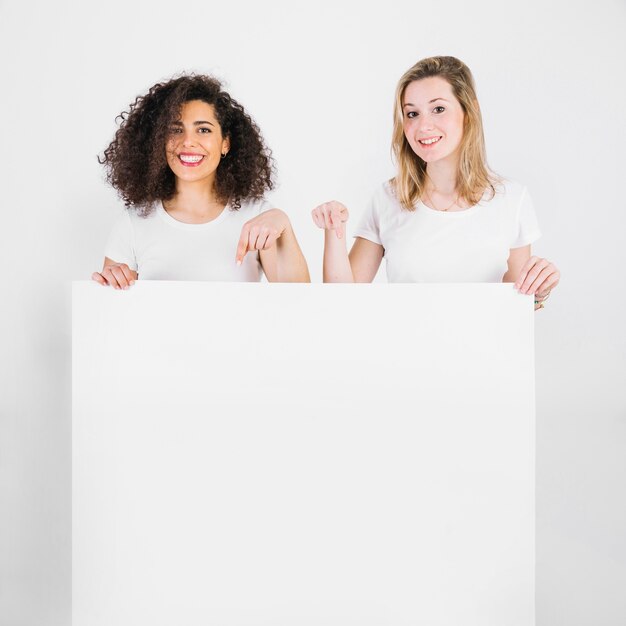 Smiling women pointing on blank poster