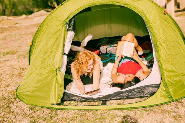 Smiling women reading books in tent