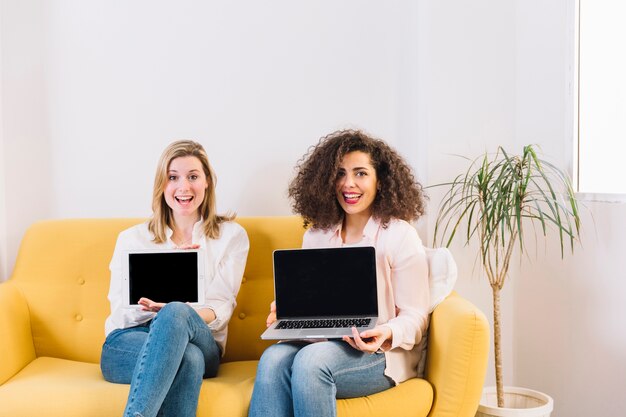 Donne sorridenti che mostrano computer portatile e compressa