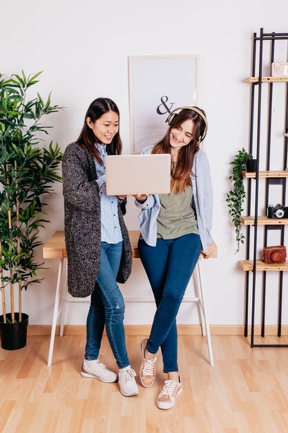 Smiling women standing and using laptop together