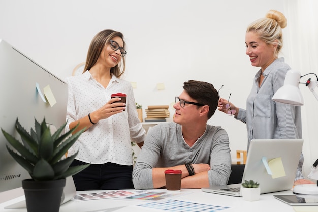 Smiling women talking with man at office