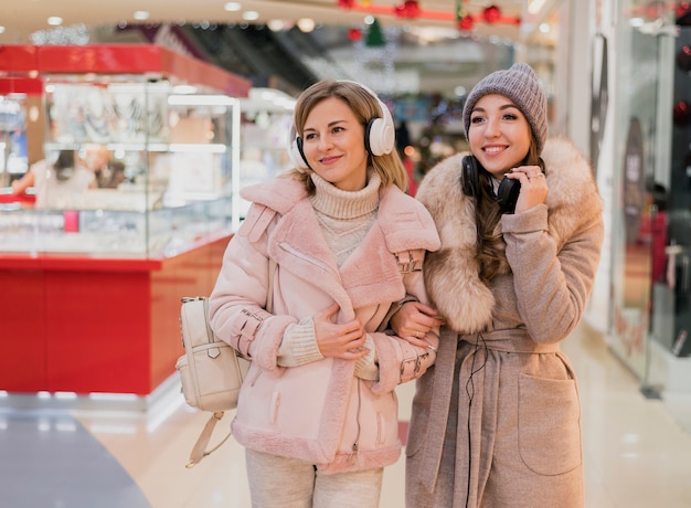 Donne sorridenti con i heaphones nel centro commerciale