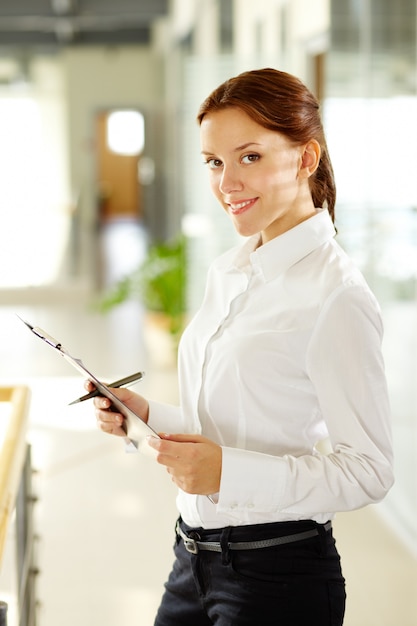 Free photo smiling worker holding a pen and a clipboard