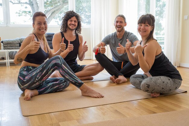 Smiling yoga students showing thumbs up