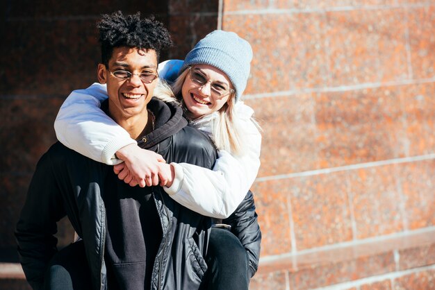 Smiling young african man carrying her girlfriend piggyback ride